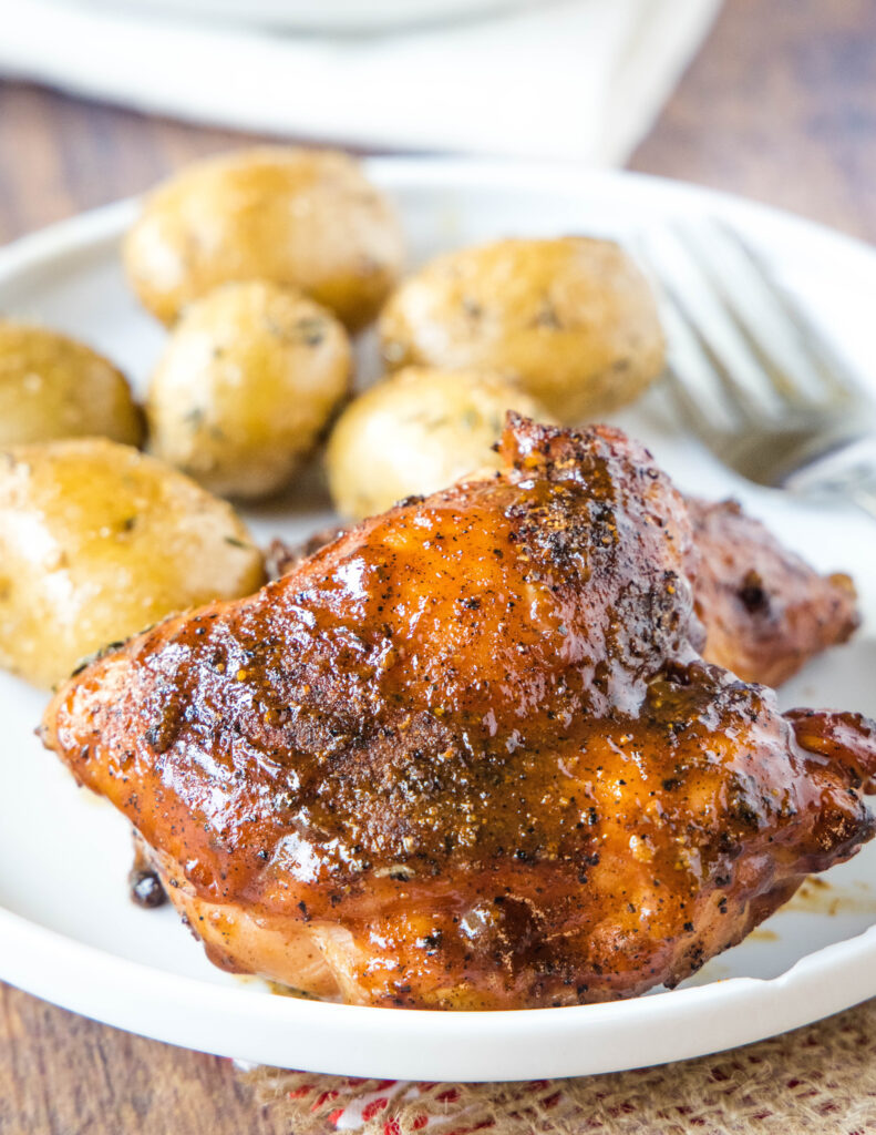 a chicken thigh on a plate with potatoes