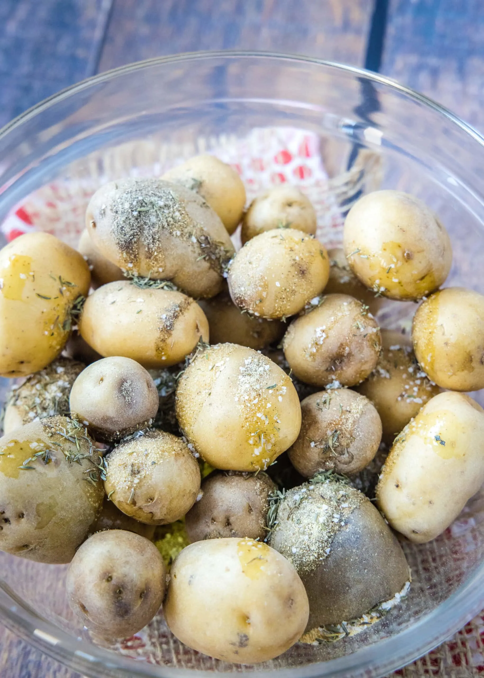seasoning potatoes in a glass bowl