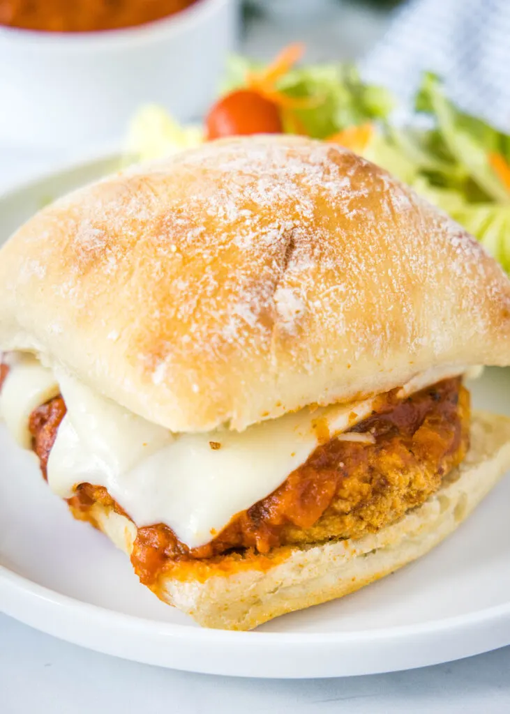 looking down on chicken parmesan sandwich on white plate