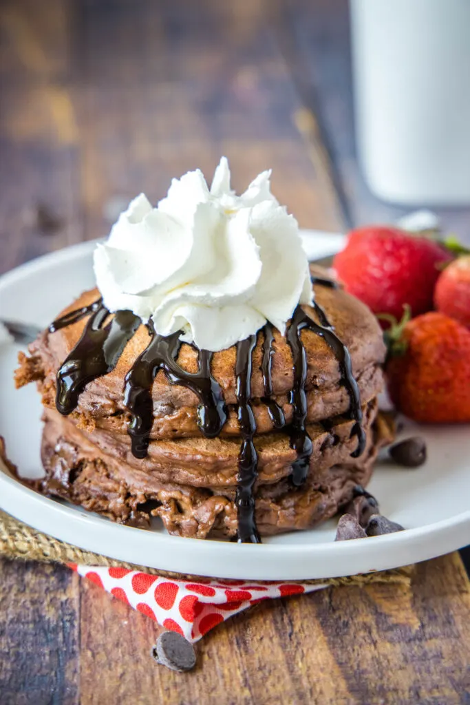 plate of chocolate pancakes with chocolate sauce and whipped cream