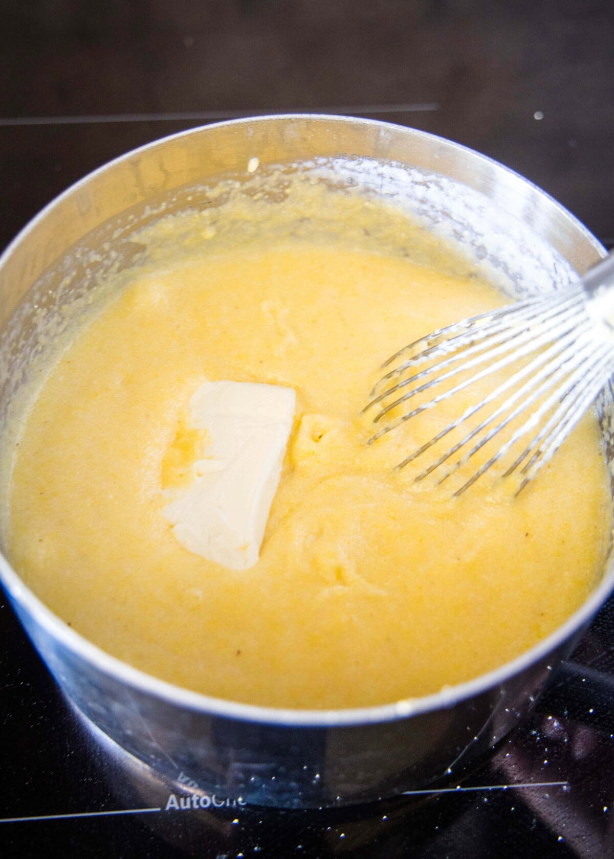adding cream cheese to cooking polenta