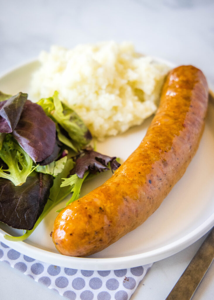 sausage on a plate with salad and potatoes
