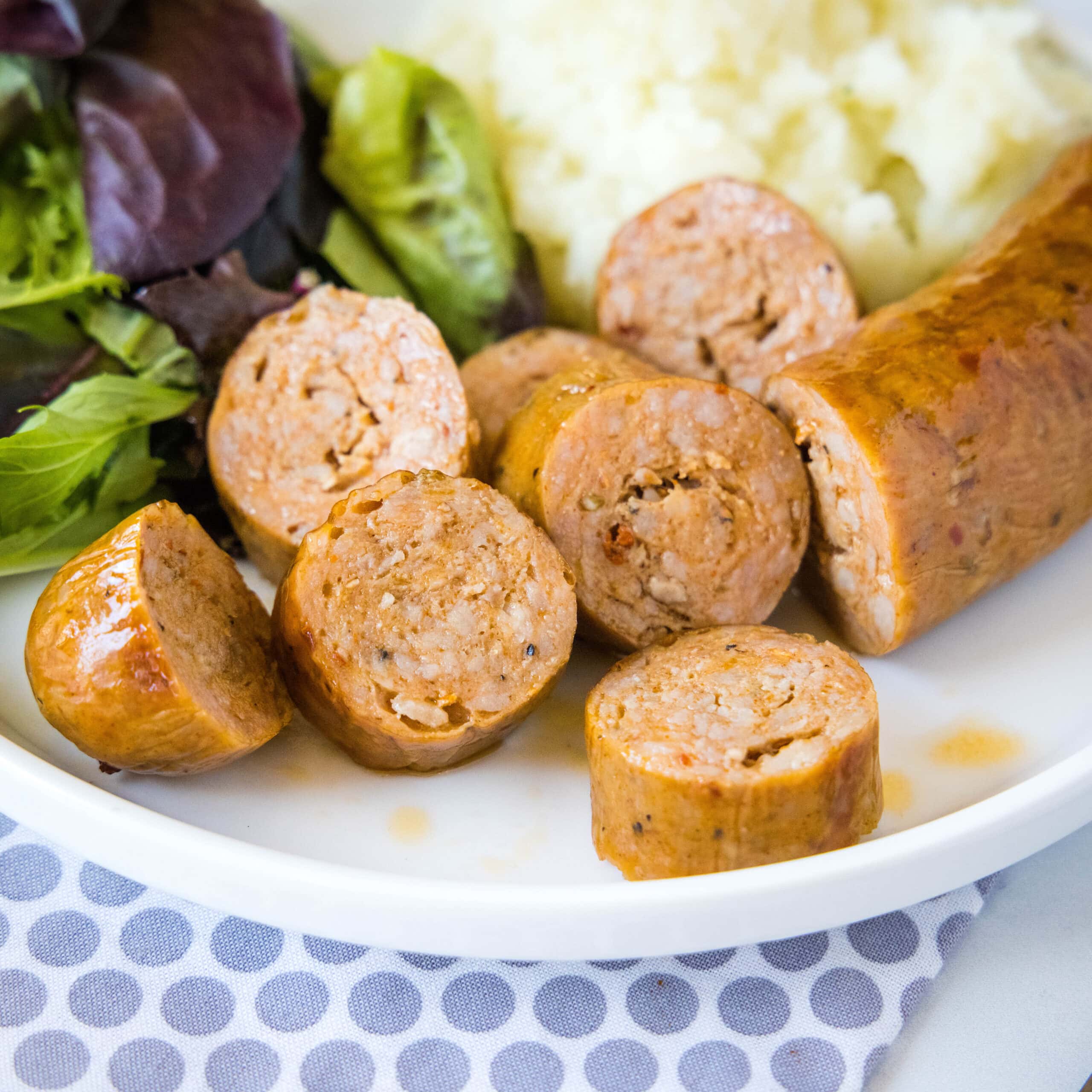 sliced sausage on a white plate with salad