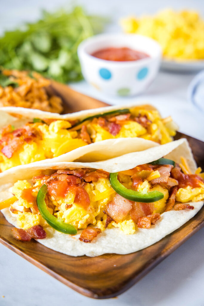 breakfast tacos with bacon on a wood plate