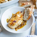 baked french onion chicken in a bowl with a slice of bread