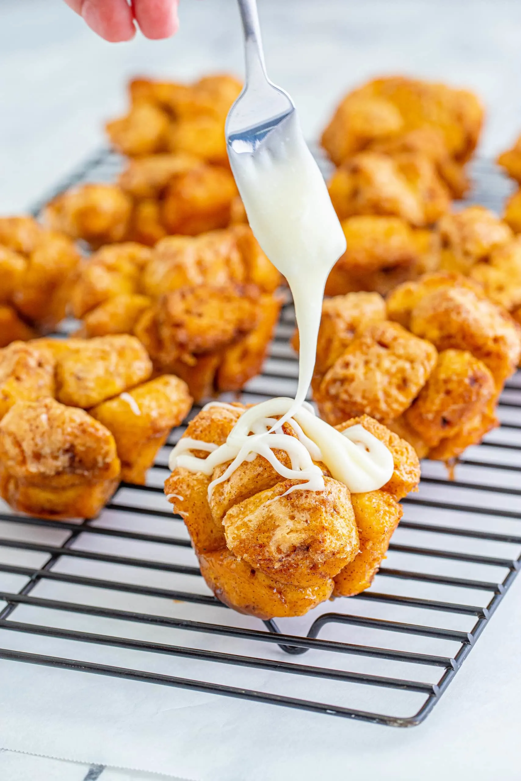 drizzling icing over monkey bread muffins