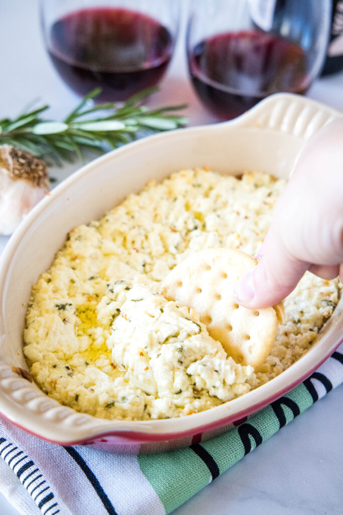 scooping goat cheese dip out with a cracker