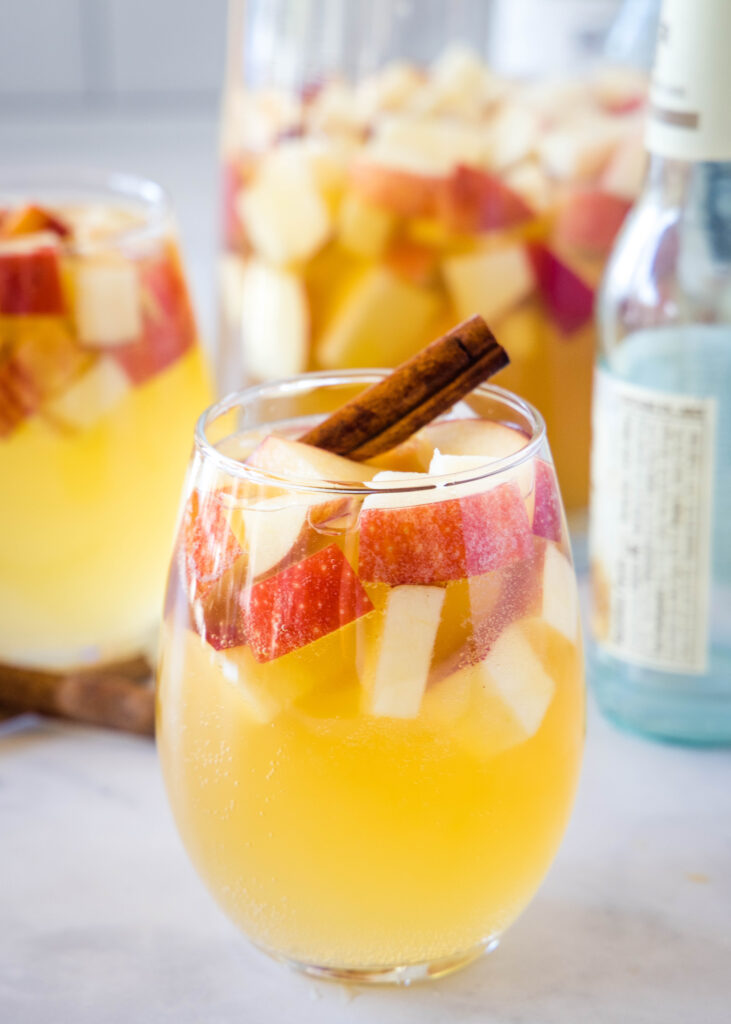 glass of fall sangria full of apples and a cinnamon stick