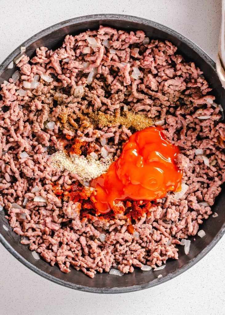 ground beef in a skillet with tomato sauce and spices