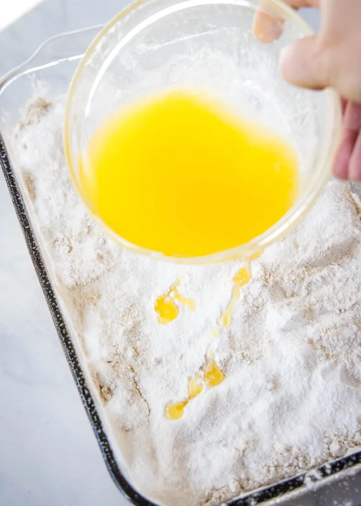 pouring melted butter over dump cake
