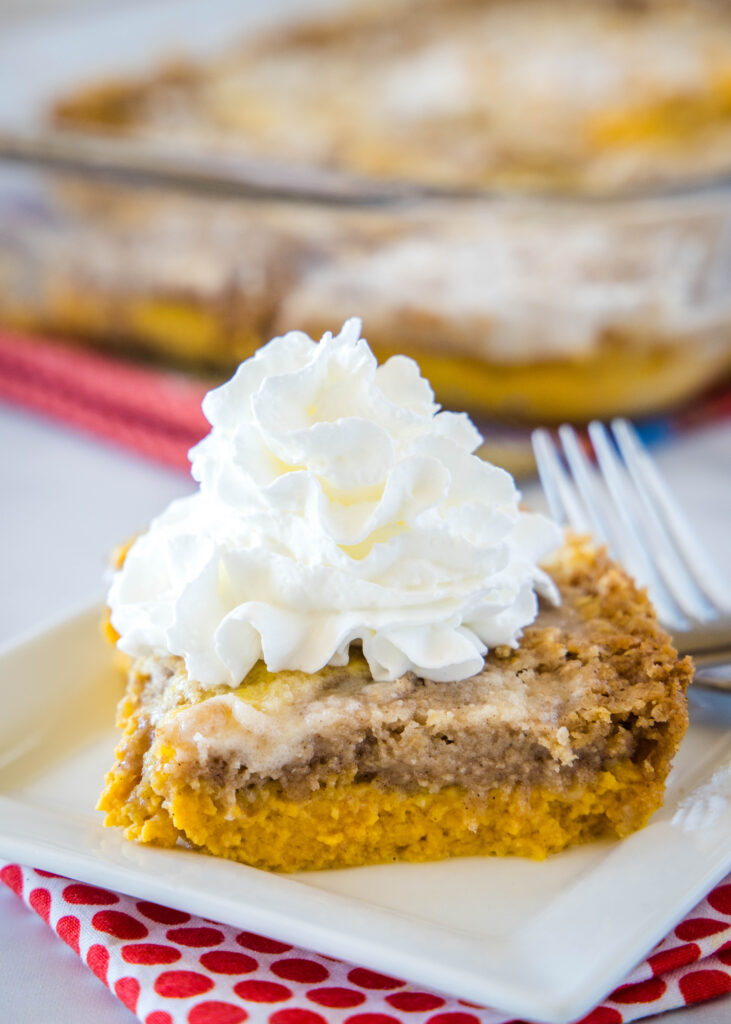 slice of pumpkin dump cake on a plate topped with whipped cream