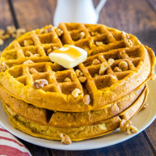 close up stack of pumpkin waffles with pat of butter on top