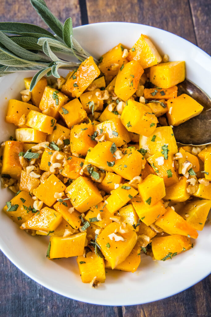 roasted butternut squash tossed with sage and walnuts in a bowl