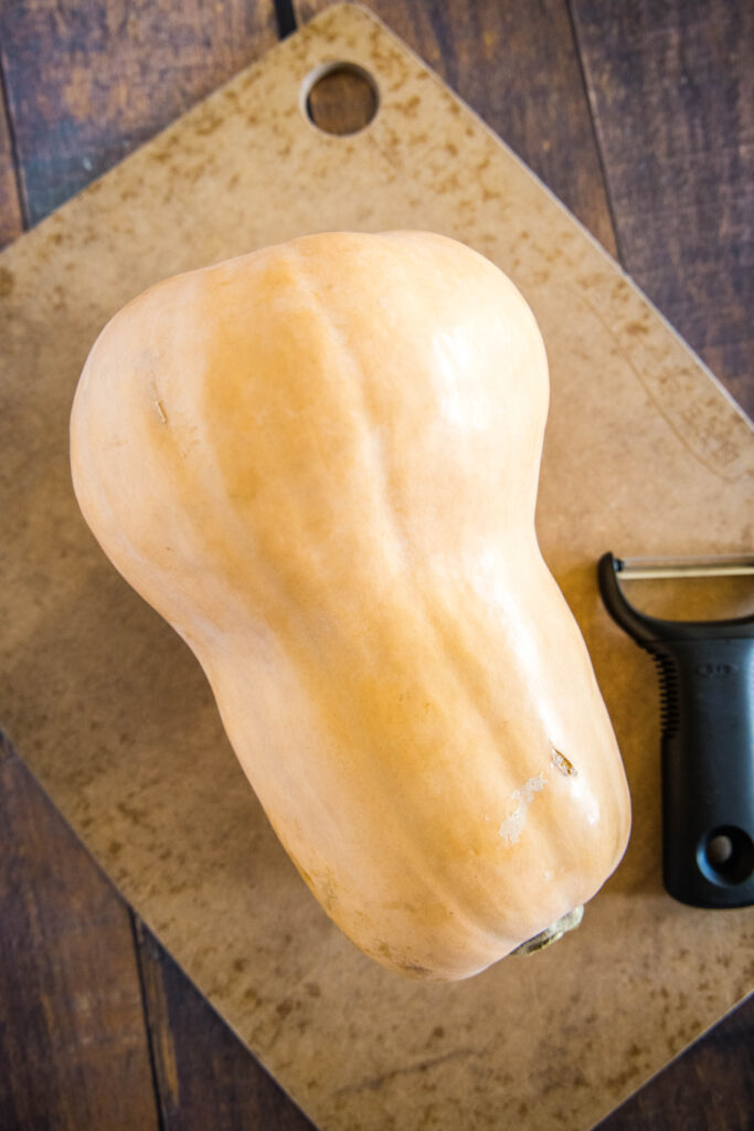 butternut squash on a cutting board ready to be peeled