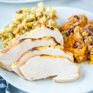 close up of sliced turkey on a plate with sweet potatoes and stuffing