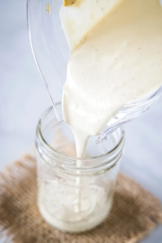 pouring blended caesar dressing into a jar