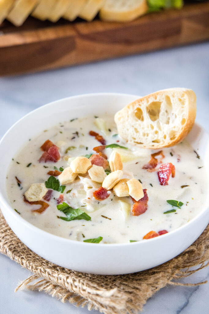 a bowl of clam chowder with a slice of bread and oyster crackers