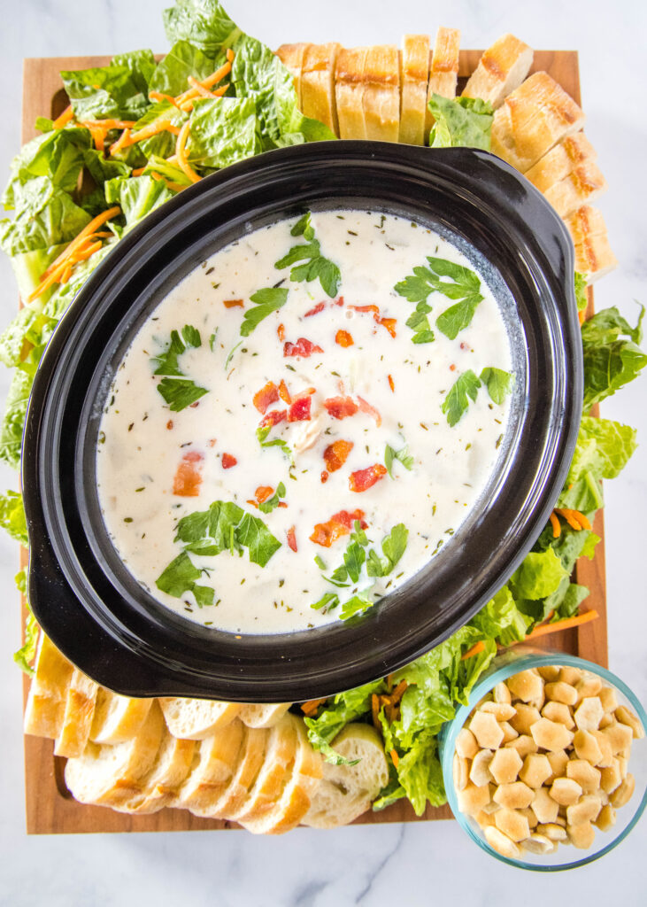 a clam chowder board with salad, bread, and oyster crackers on the side