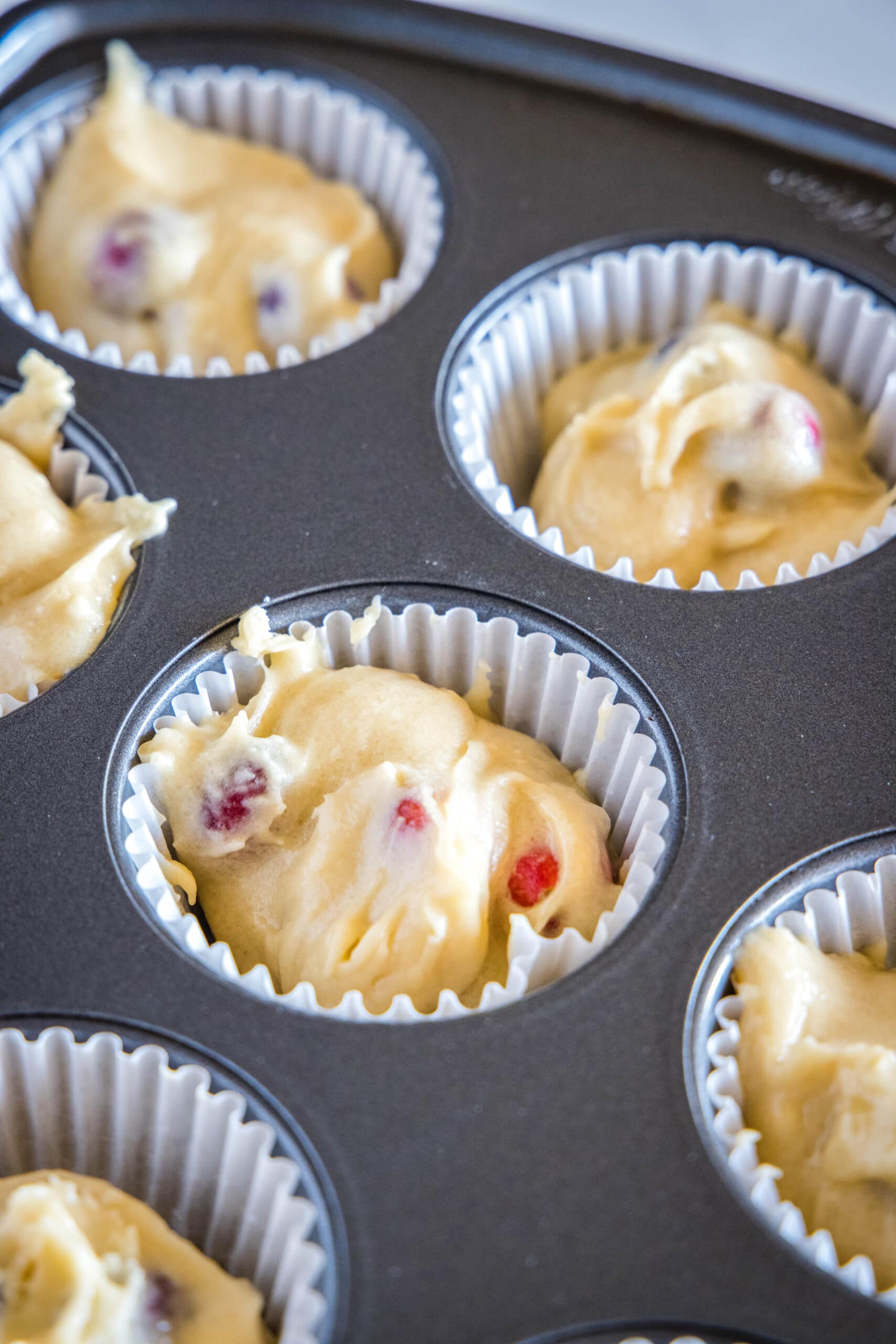 cranberry muffin batter in muffin tins
