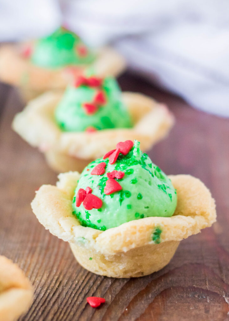 sugar cookie cups topped with green no bake cheesecake