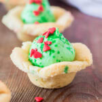cropped in close up of a grinch sugar cookie cup topped with heart sprinkles