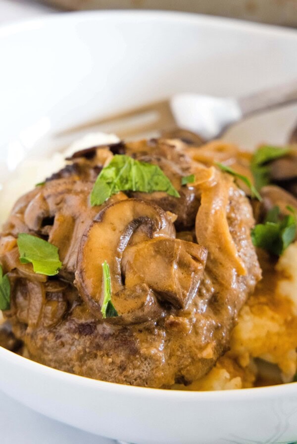 clopped in close up of salisbury steak on a white plate