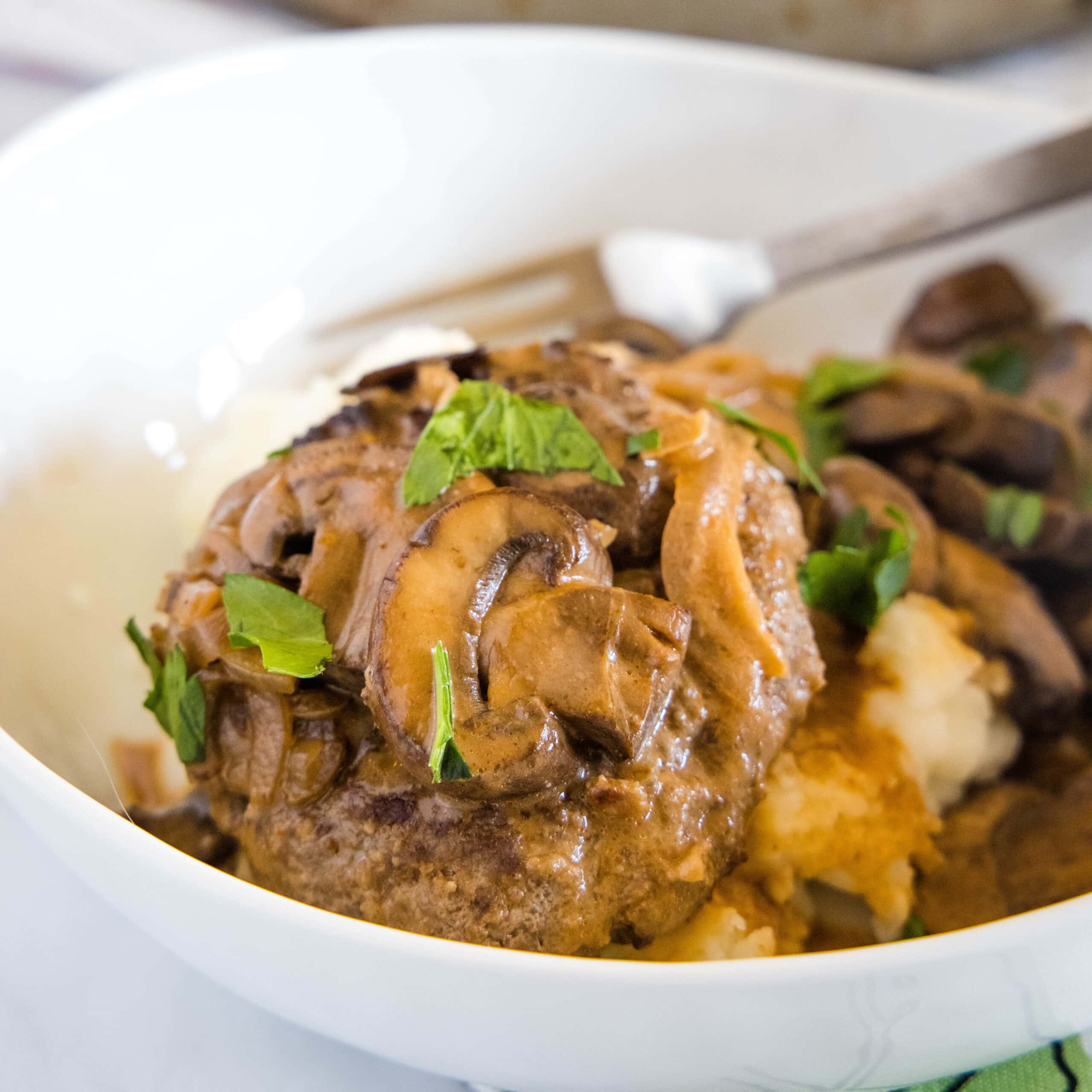 clopped in close up of salisbury steak on a white plate
