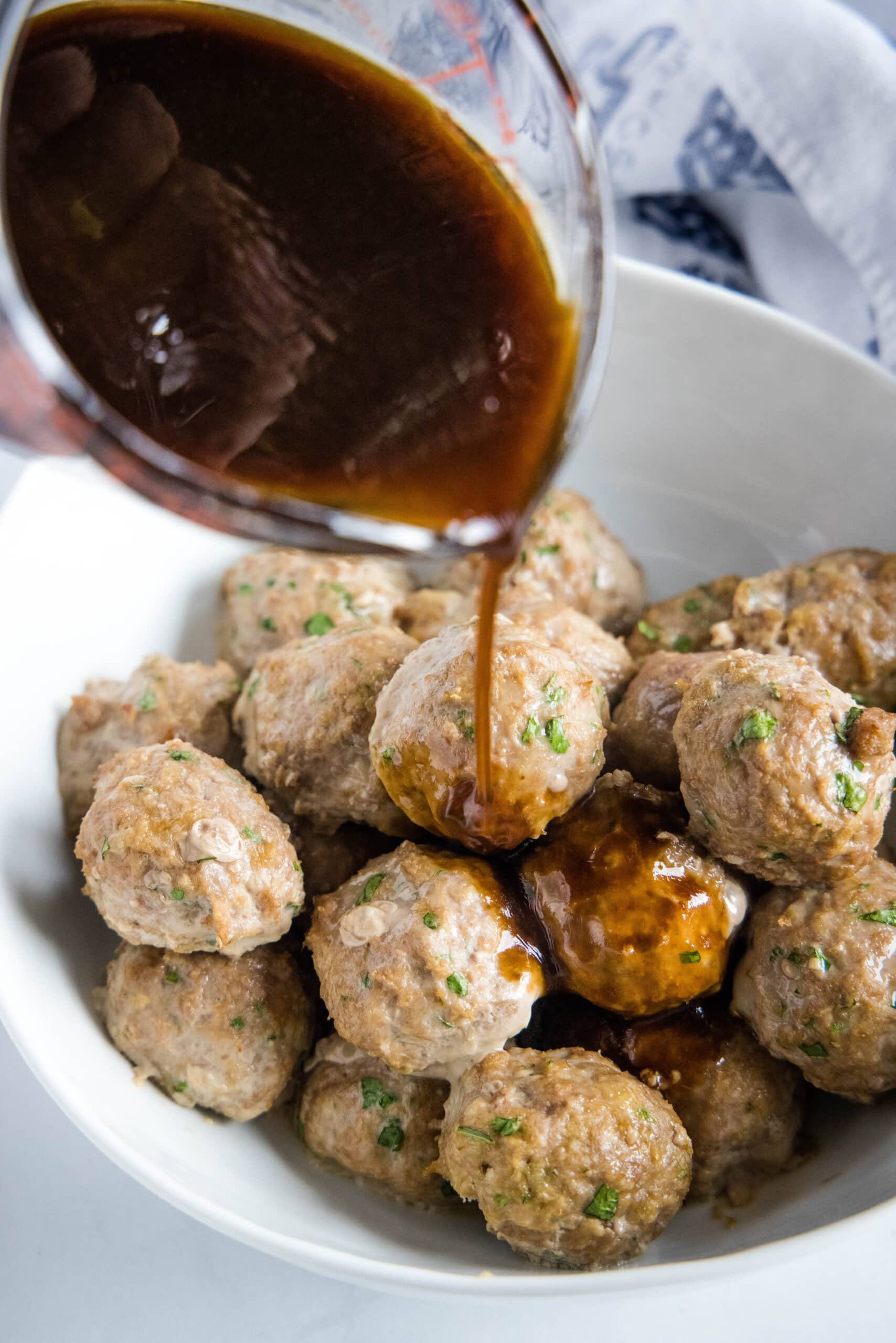 pouring sauce over turkey meatballs