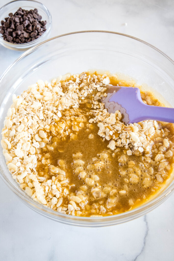 adding honey mixture to mixing bowl with oats
