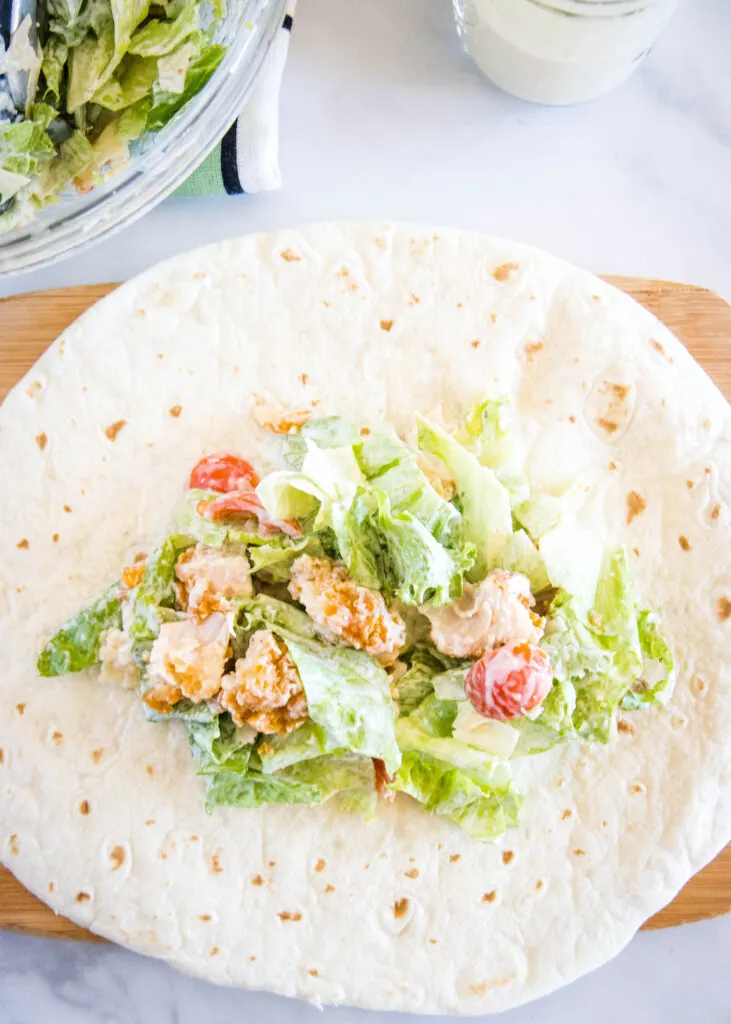 filling a wrap with chicken caesar salad