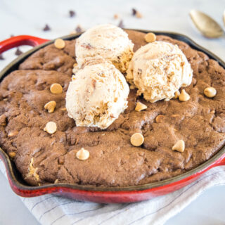 close up chocolate cookie in a skillet with ice cream and peanut butter chips