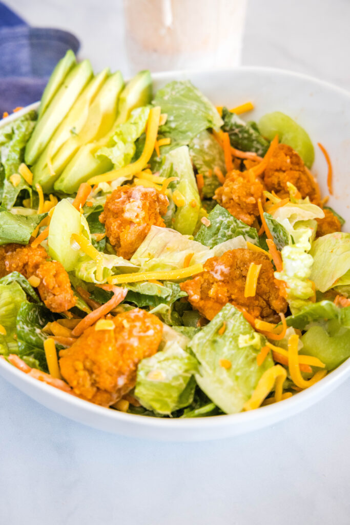 tossed buffalo chicken salad in a white bowl