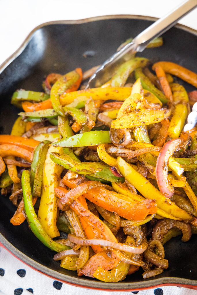 cooked bell peppers and onions in a skillet
