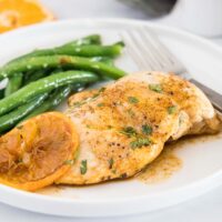 close up chicken breast with orange glaze on white plate