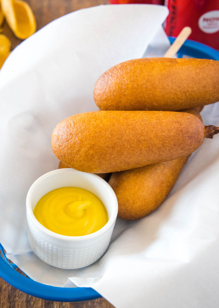 corn dogs stacked in a basket with parchment paper