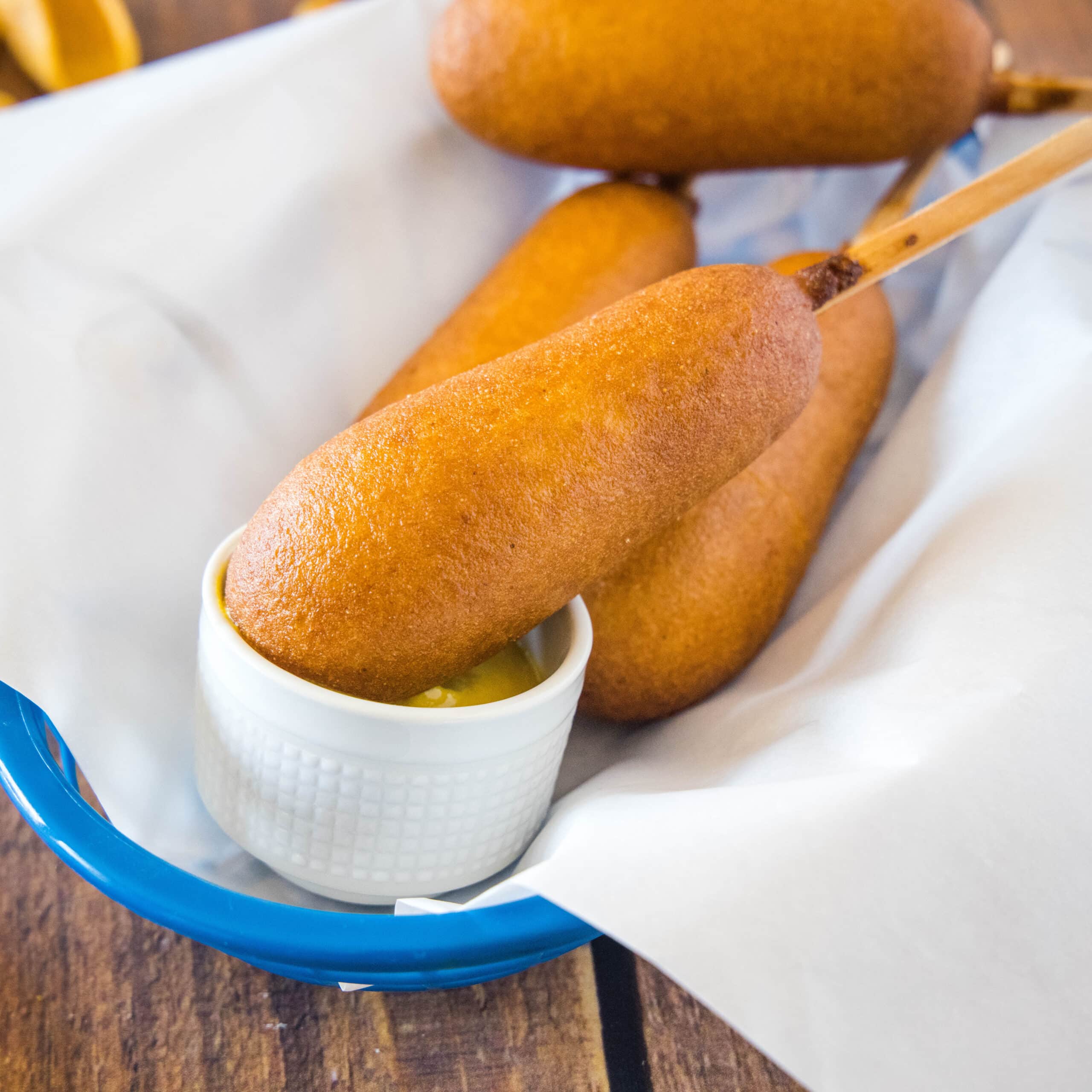 close up corn dog dipping in mustard