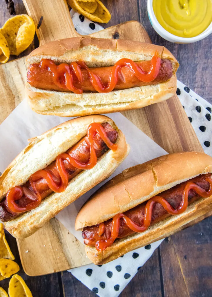 hot dogs topped with ketchup on a cutting board