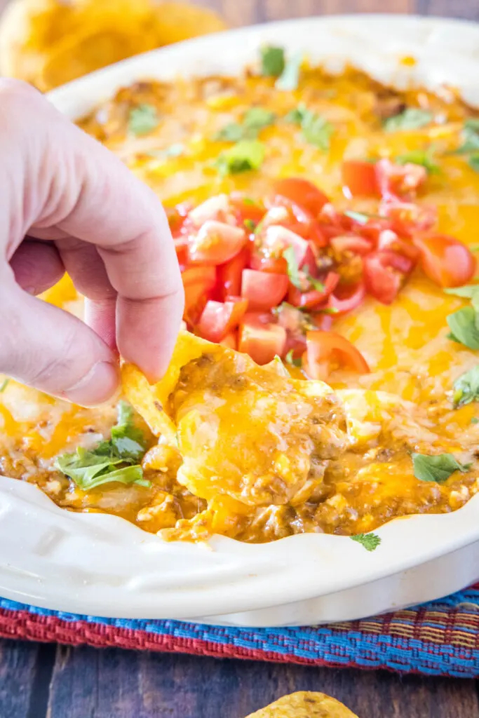 using a chip to scoop out cheese dip