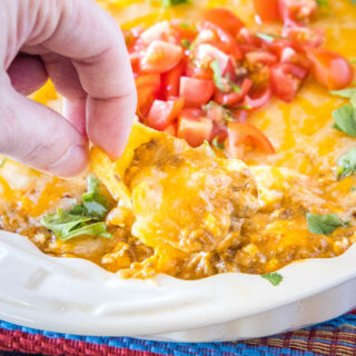 close up using a chip to scoop out chili cheese dip