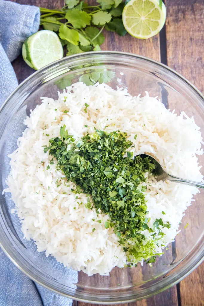 adding cilantro and lime to a bowl of rice