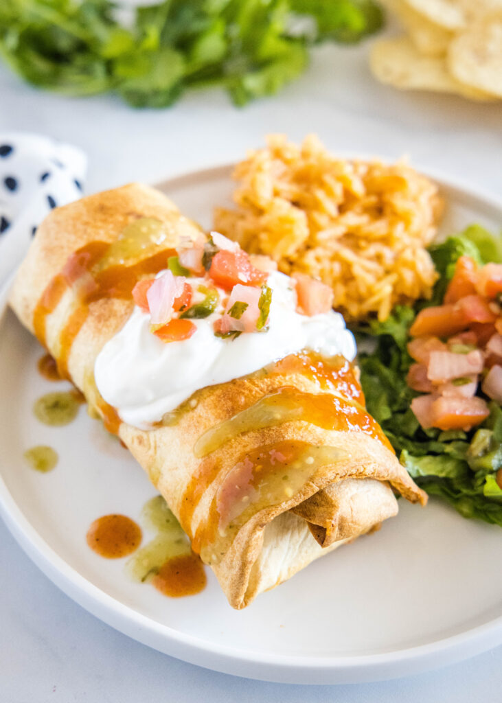 chimichanga on a plate with sour cream on top
