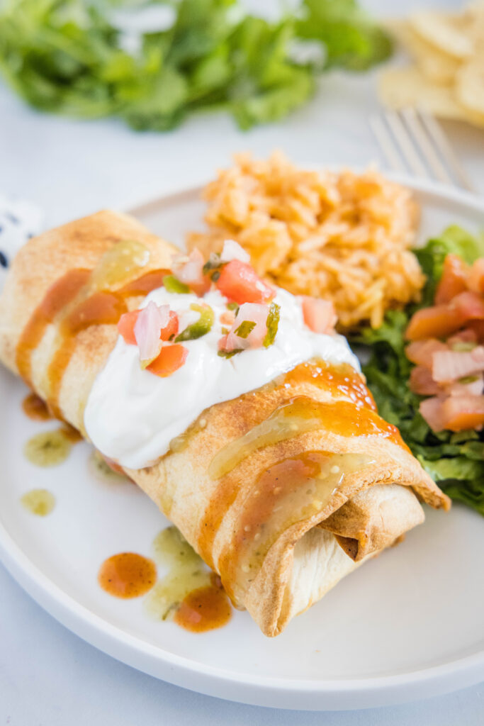 air fryer chimichanga on a plate topped with sour cream