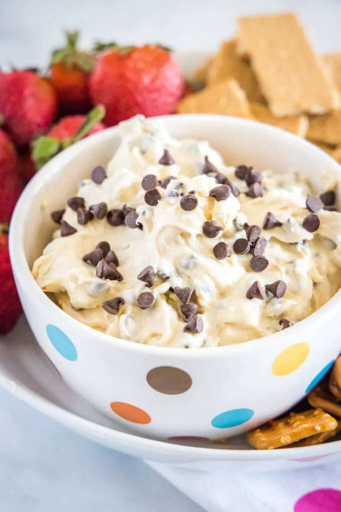 bowl of cookie dough dip with strawberries and graham crakers around it