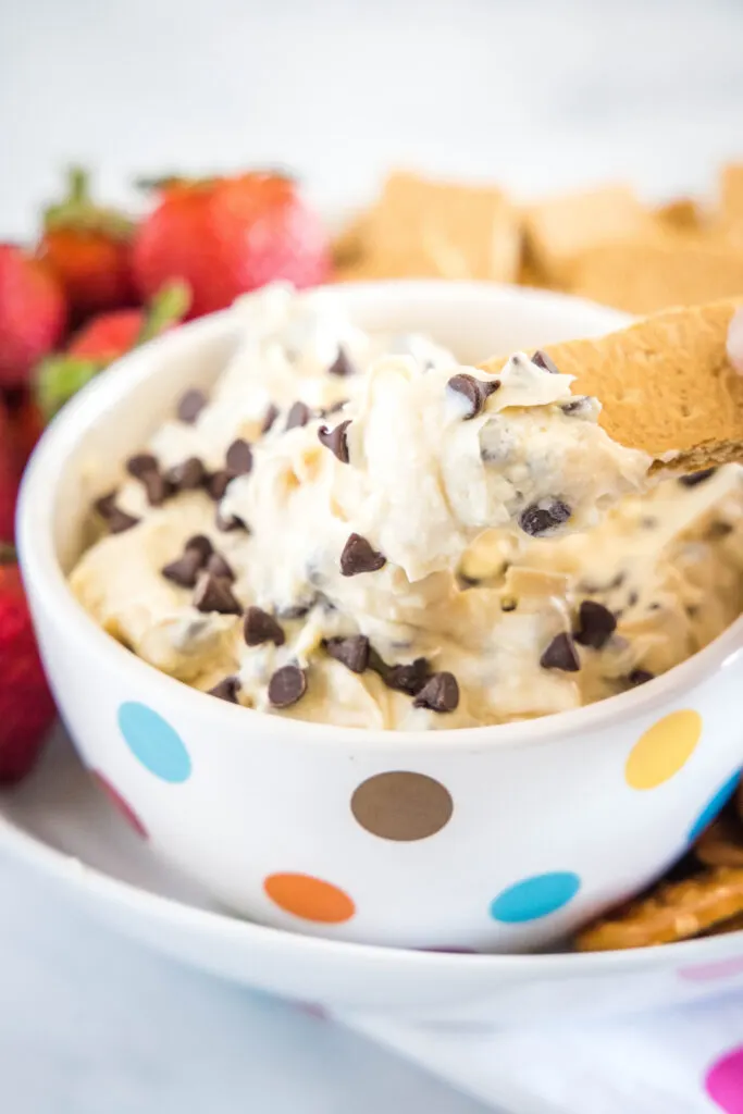 scooping cookie dough dip out with a graham cracker