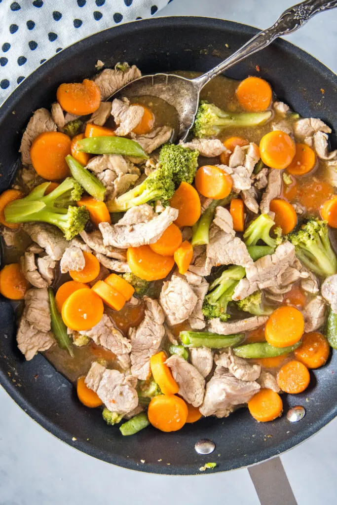 looking down on a skillet with pork and veggies in it