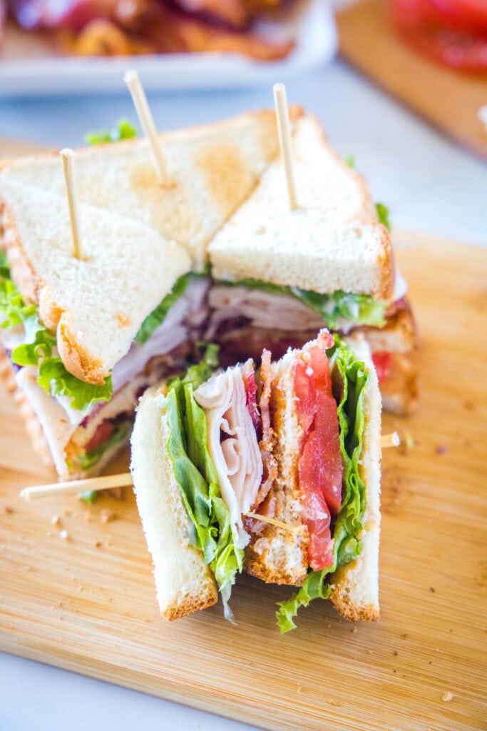 turkey club sandwich sliced into quarters on a cutting board