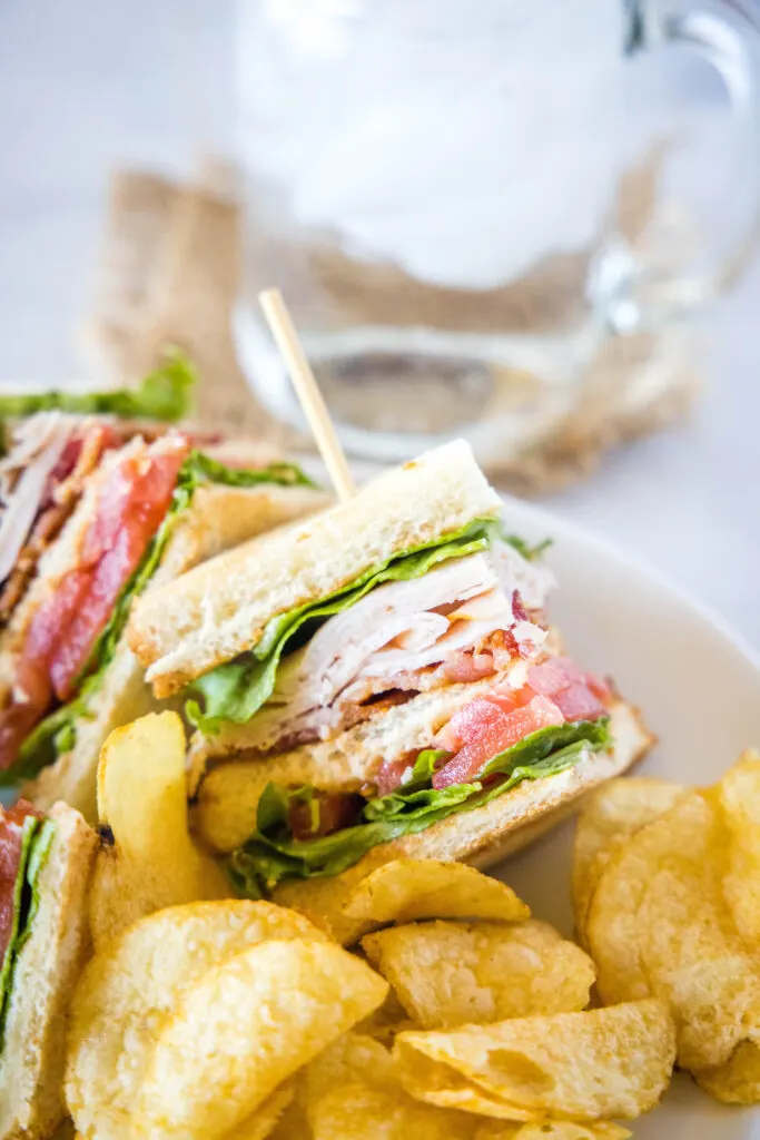 turkey club sandwich on plate with chips