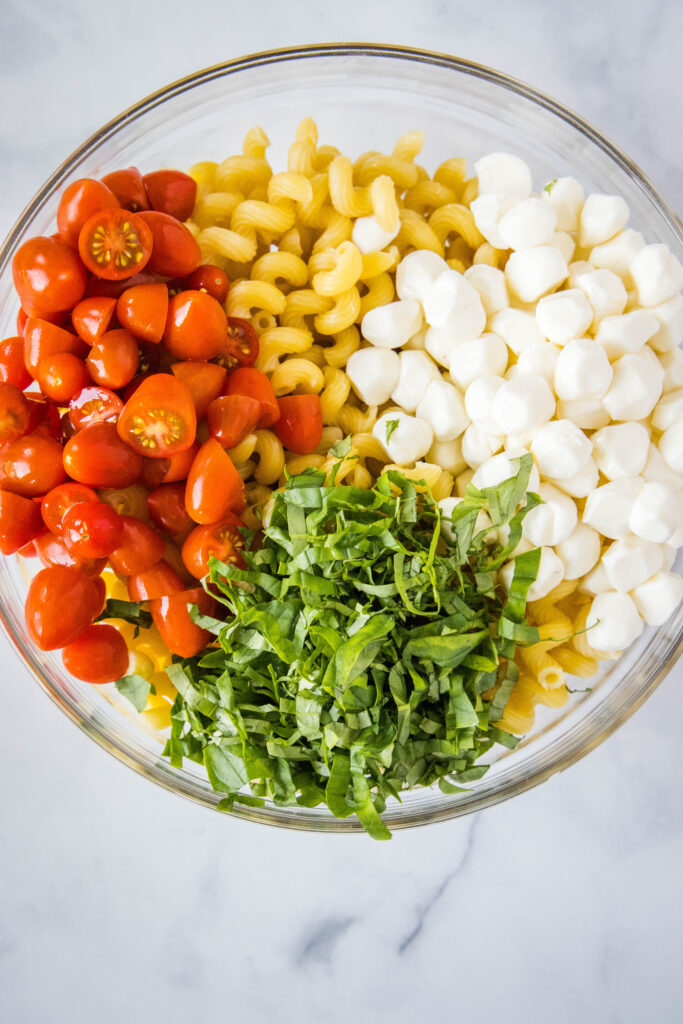 pasta, tomatoes, basil and mozzarella cheese in a bowl