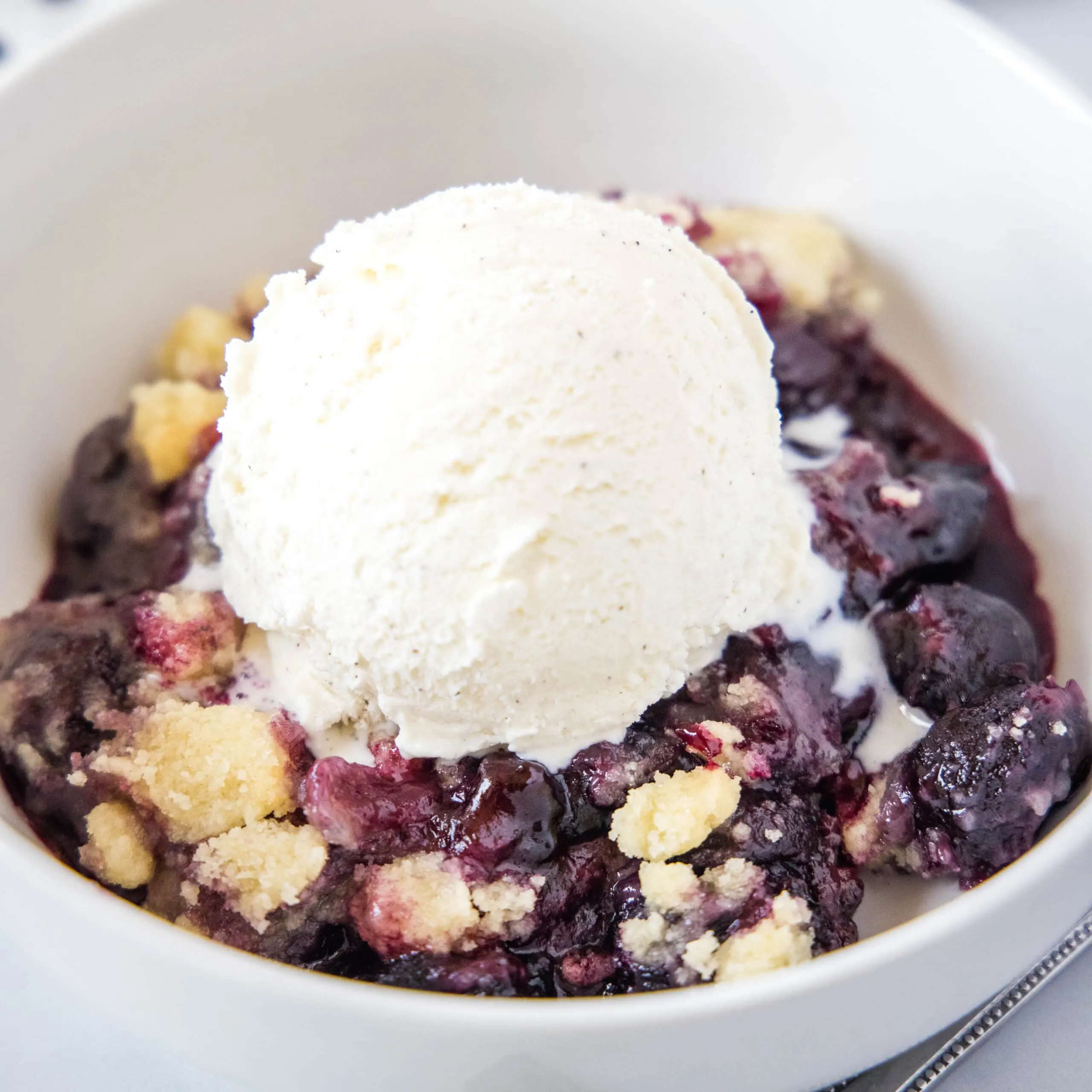 close up cherry cobbler with ice cream in a bowl