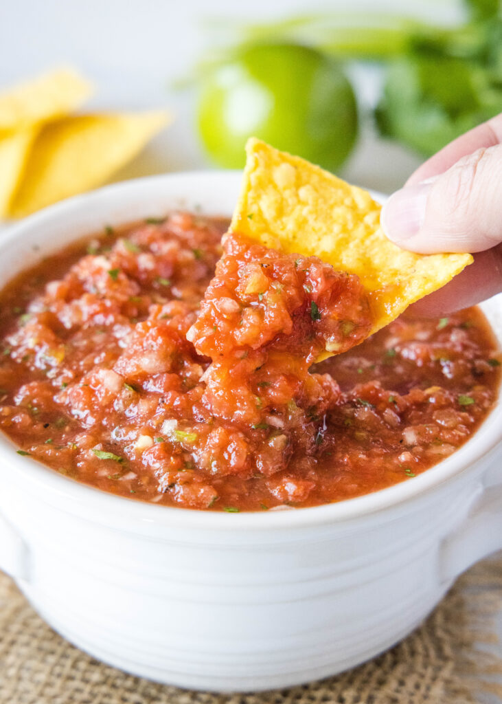 scooping salsa out of a bowl with a tortilla chip